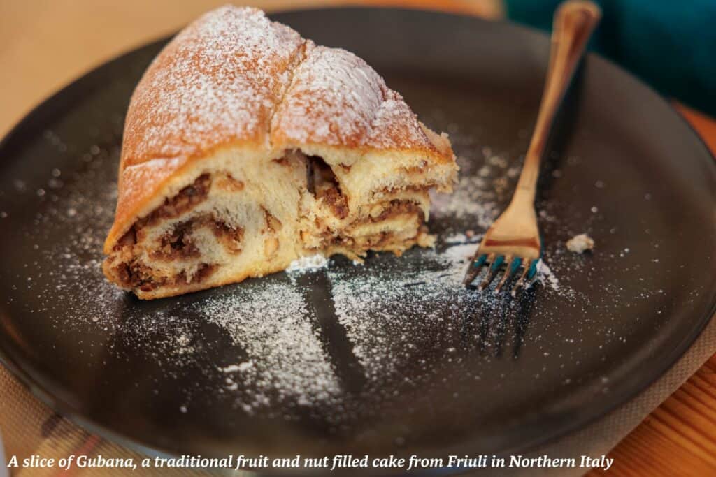 Slice of gubana cake on a plate dusted with icing sugar - culinary guide to Friuli Venezia Giulia