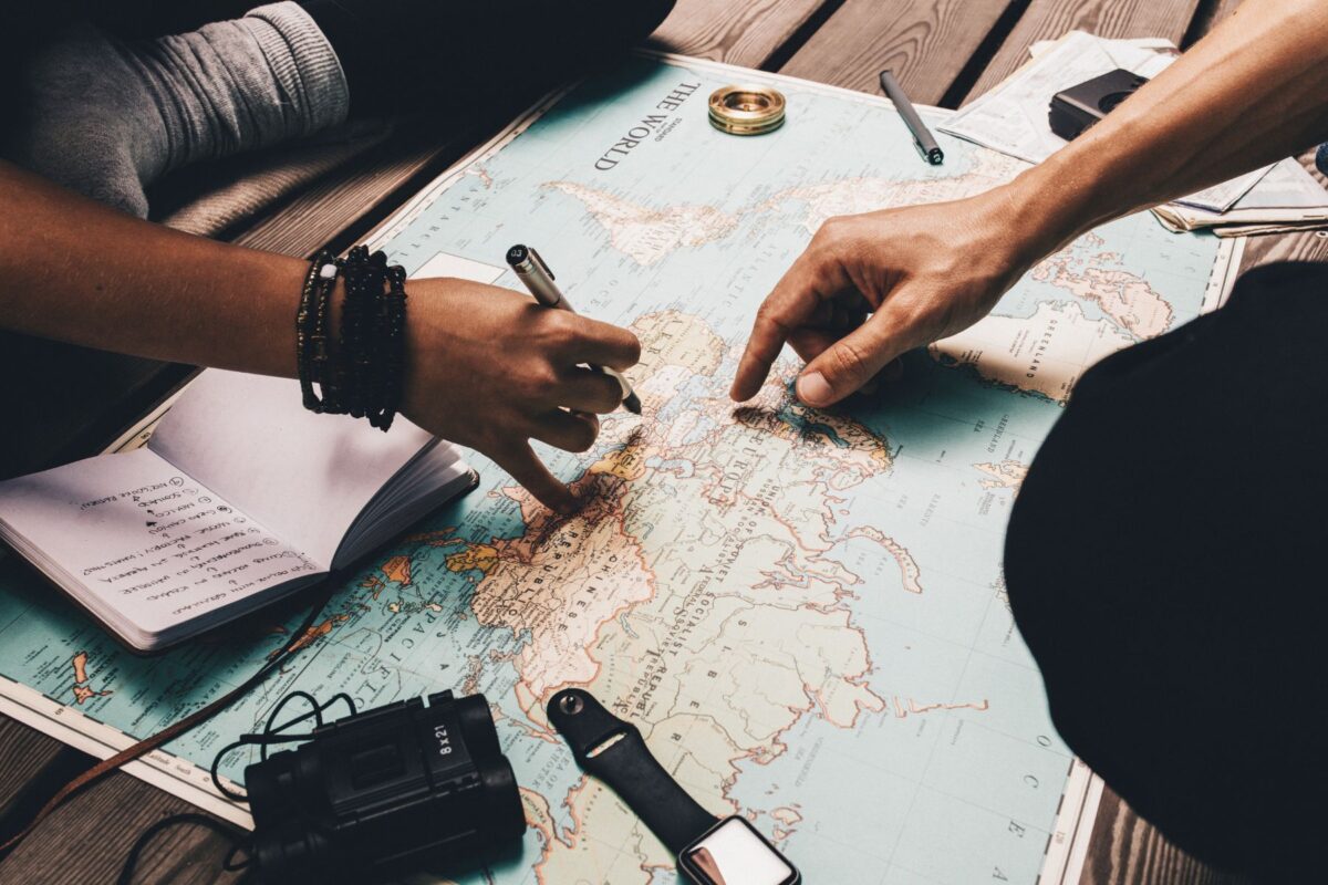 A couple cross-legged with a map on the floor, planning a journey